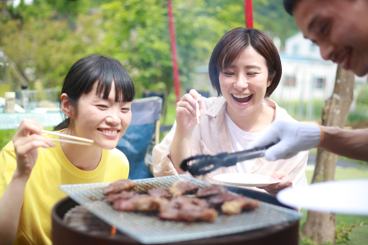 Personnes partageant un barbecue japonais en extérieur autour d’un grill.